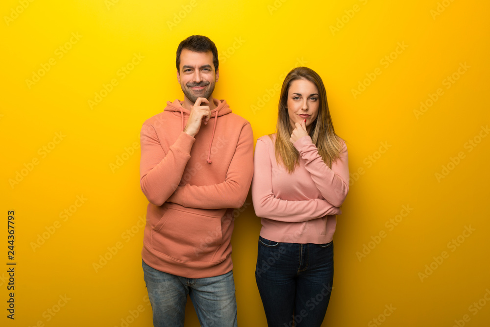 Fototapeta premium Grupa dwóch osób na żółtym tle, uśmiechając się i patrząc do przodu z pewną siebie miną