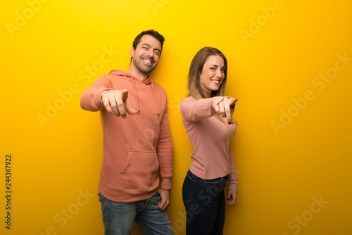 Group of two people on yellow background points finger at you with a confident expression
