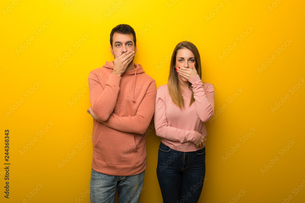 Fototapeta premium Group of two people on yellow background covering mouth with hands for saying something inappropriate
