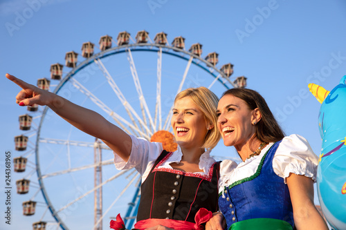 2 junge sexy Frauen haben Spass auf dem Frühlingsfest, Oktoberfest, Wiesn, mit Lebkuchenherz Schokobane vor dem Riesenrad Luftballons