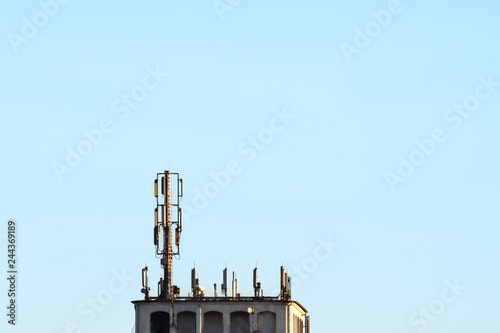 Antennae for mobile phones on a roof in front of a blue sky