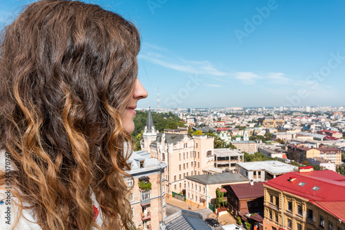 View of Kyiv old historic town cityscape skyline with buildings in Kiev city and young woman happy looking through window during sunny summer day