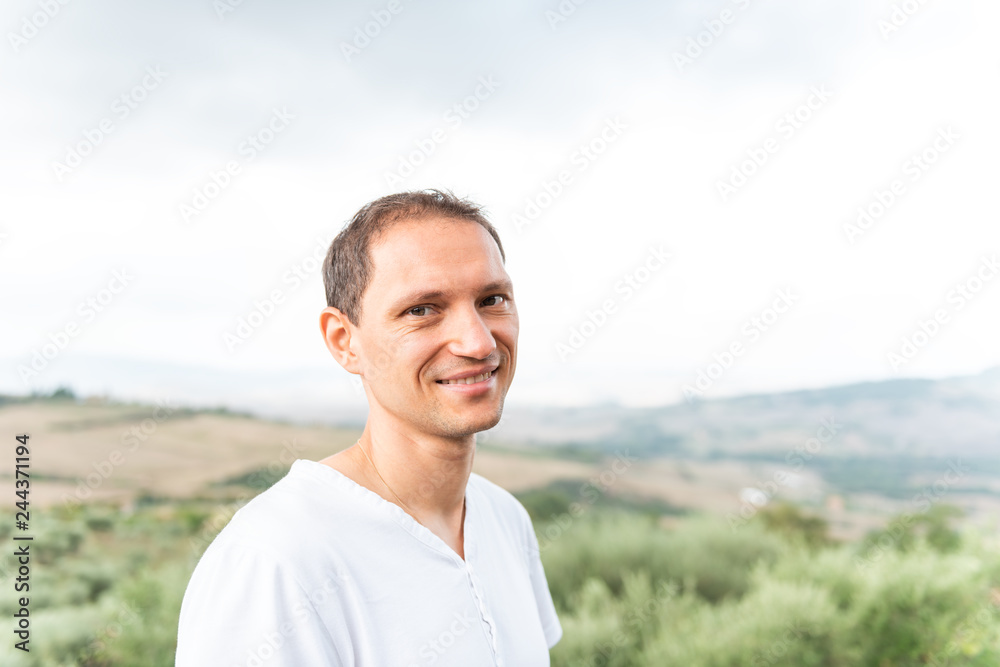Val D'Orcia countryside in Tuscany, Italy with rolling green hills with farm landscape idyllic picturesque meadow fields and smiling young man Val D'Orcia countryside in Tuscany, Italy with rolling green hills with farm landscape idyllic picturesque meadow fields and smiling young man