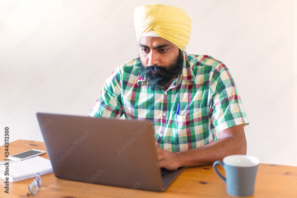 Indian with turban working with his laptop Indian with turban working with his laptop