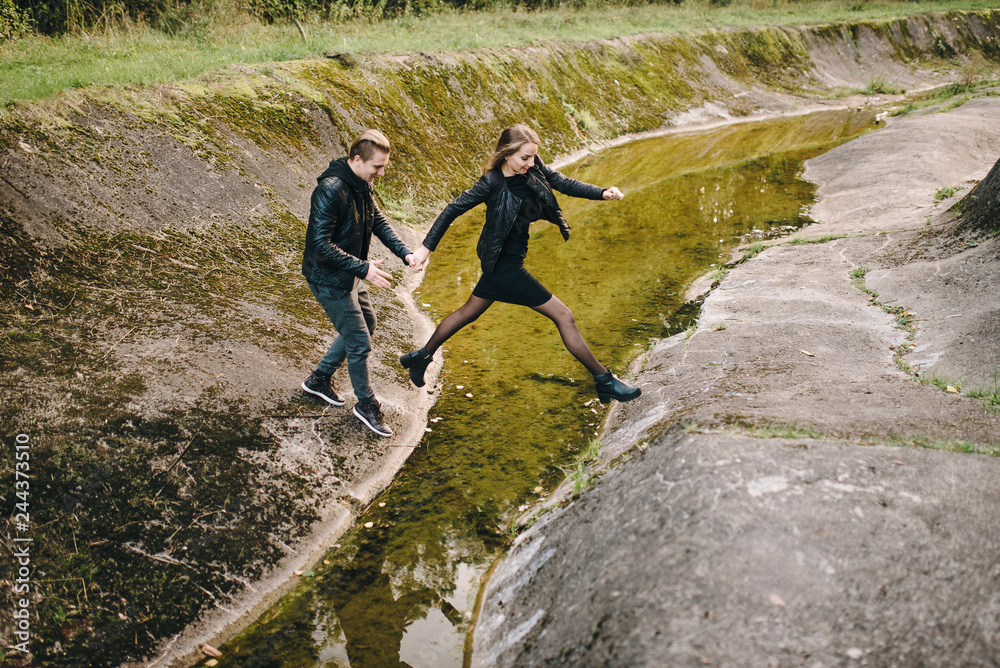 Obraz premium Young couple jumping over stream