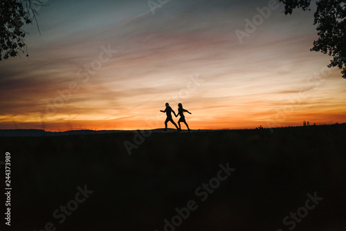 Young couple running by the sea and looking at the sun