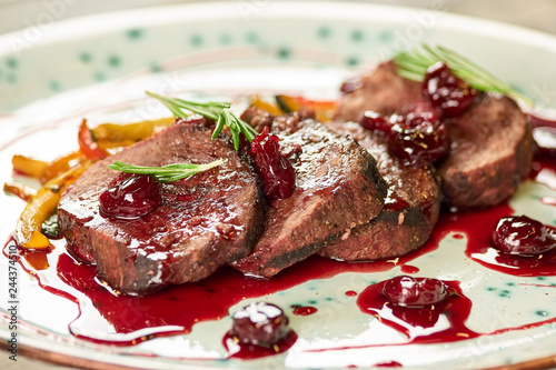 Grilled veal with smashed cherries, closeup. Veal with smashed cherries, rosemary and yellow pepper. photo