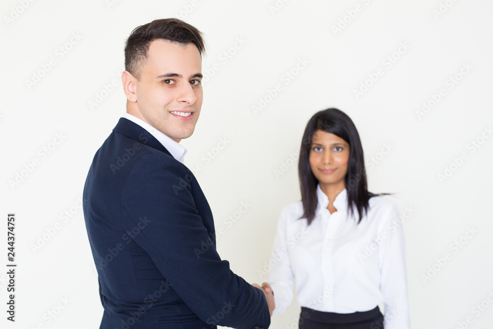 Smiling business colleagues greeting each other. Positive young man and woman in office clothes shaking hands. Handshake deal concept Smiling business colleagues greeting each other. Positive young man and woman in office clothes shaking hands. Handshake deal concept