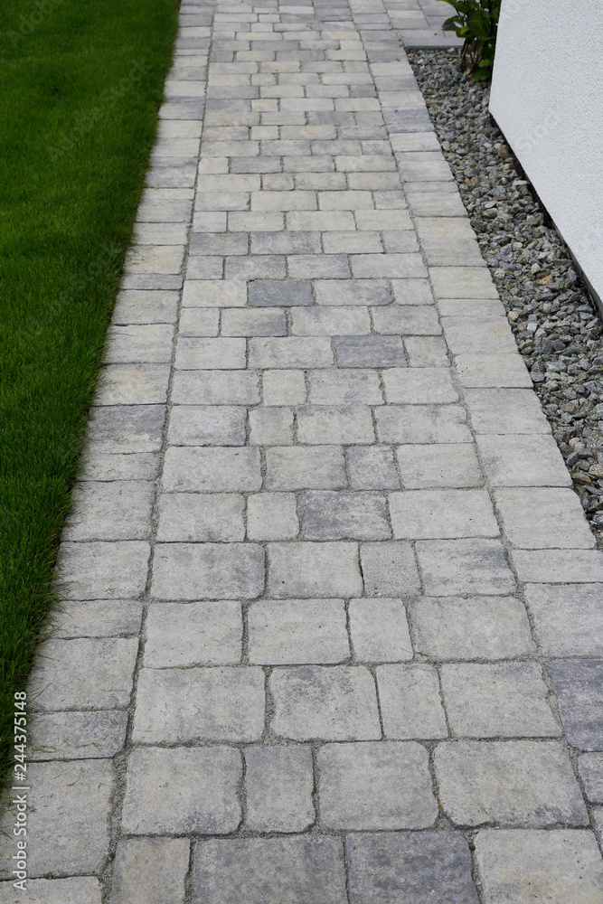 Moderner Gartenbau Gehweg aus Natursteinen entlang einer Hauswand