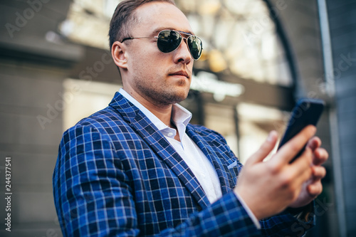 close portrait of a man. businessman holding a phone. wearing a blue jacket and a white shirt. busy
