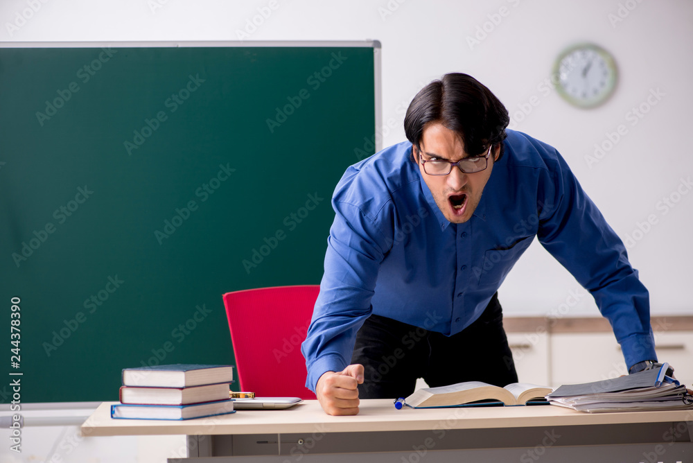 Young male teacher in front of chalkboard Young male teacher in front of chalkboard