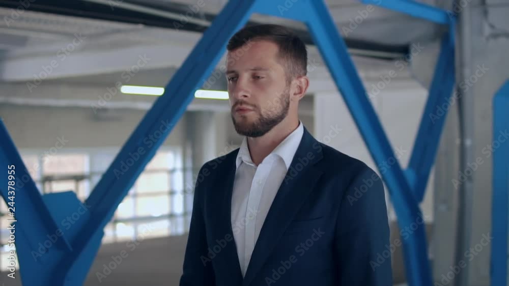 candid man wearing elegant blue suit walks in storage with white wall. handsome businessman walking on factory slow motion. candid man wearing elegant blue suit walks in storage with white wall. handsome businessman walking on factory slow motion.