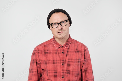 Young european man in red shirt dissatisfied frowns and looks sullenly. © Viktor Koldunov