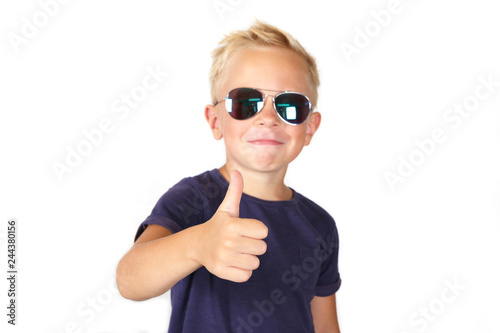 Fototapeta Naklejka Na Ścianę i Meble -  Cute blond boy wearing sunglasses showing Thumbs Up