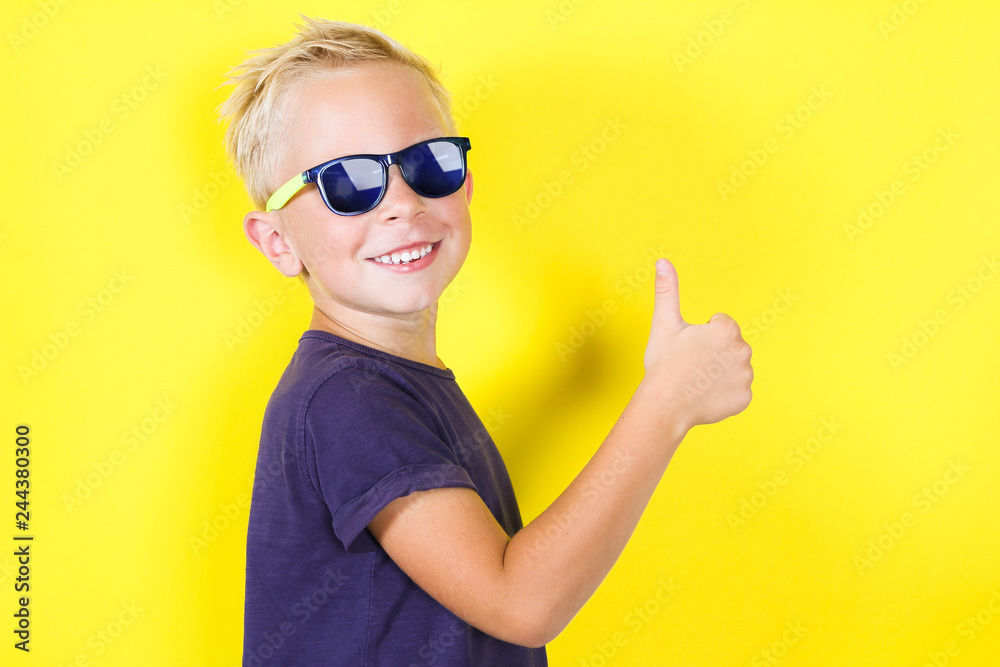 Cute blond boy wearing sunglasses showing Thumbs Up