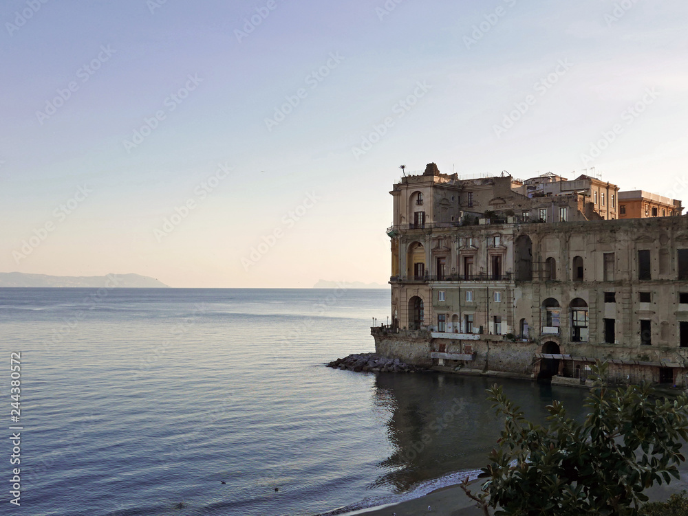 il mare di napoli e un palazzo storico con i colori del tramonto