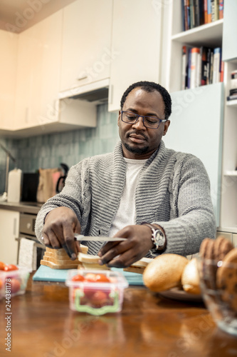 African-American man making sandwiches with bacon and veggies