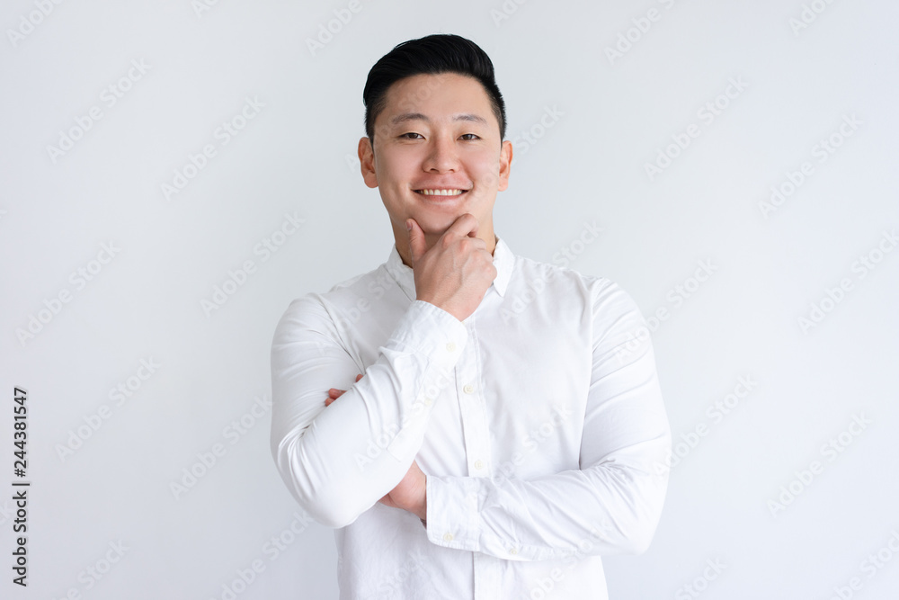 Happy Asian man touching chin and looking at camera. Positive handsome guy standing and posing. Asian man portrait concept. Isolated front view on white background. Happy Asian man touching chin and looking at camera. Positive handsome guy standing and posing. Asian man portrait concept. Isolated front view on white background.