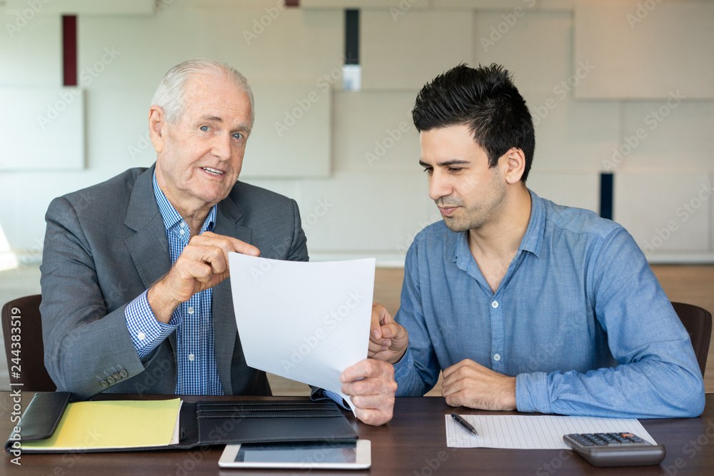 Meeting of business people of different generations. Positive senior businessman talking to young colleague at meeting. Communication concept Meeting of business people of different generations. Positive senior businessman talking to young colleague at meeting. Communication concept
