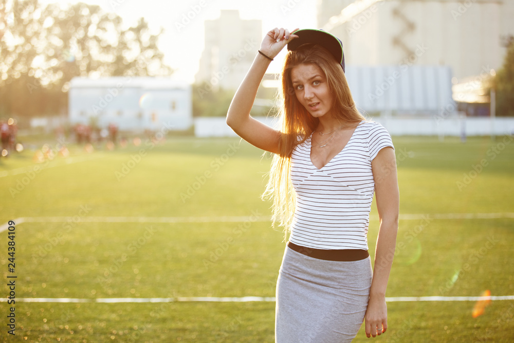 Obraz premium Beautiful girl posing for photo on sports playground at sunset