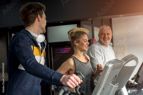 Group of smiling people exercising together on treadmills in gym and enjoy workout 
