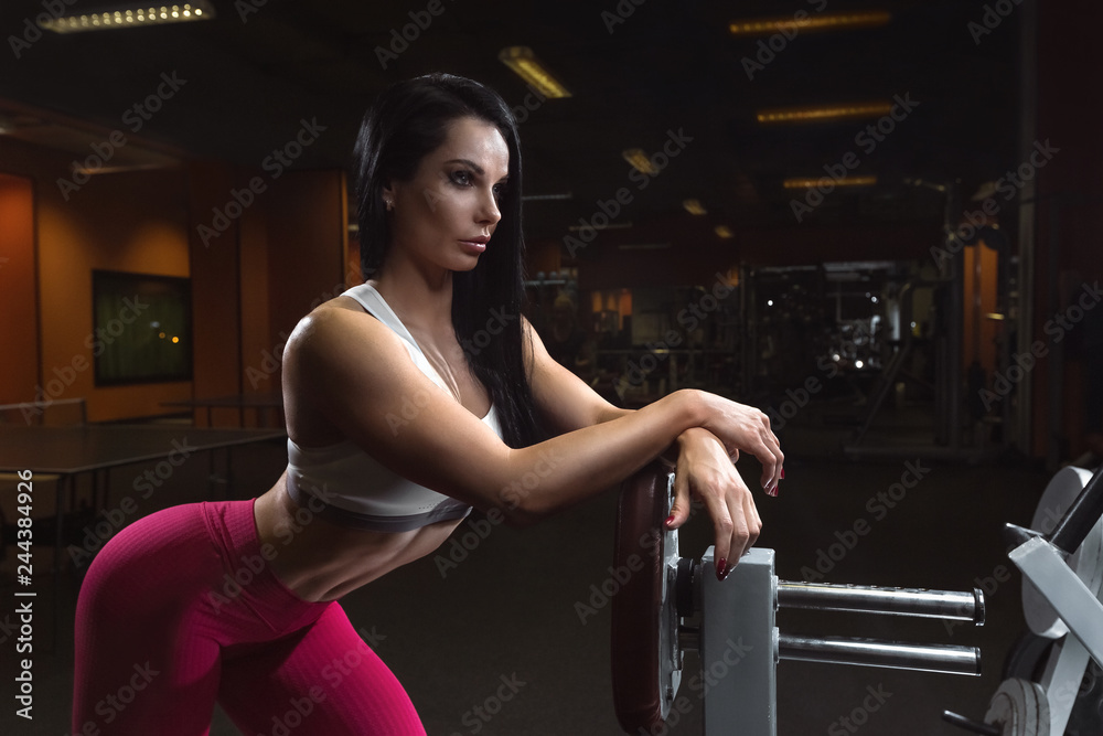 Sexy fitness woman is standing near the training apparatus, posing in the gym Sexy fitness woman is standing near the training apparatus, posing in the gym
