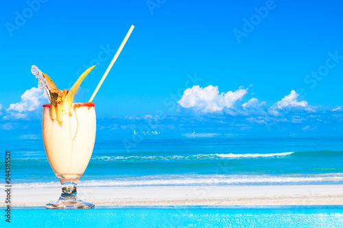 Refreshing pina colada cocktail against water oceam and amazing beach background. Summer vacation concept. photo