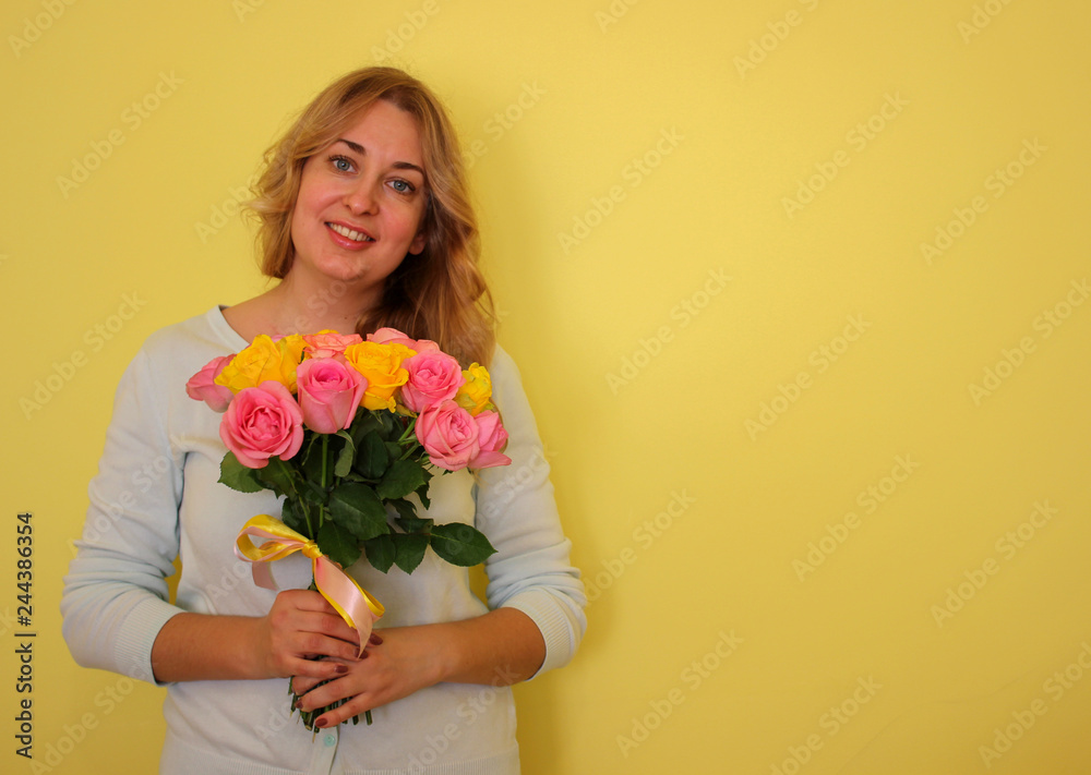 .Beautiful blond girl in the blue dress holding bouquet of yellow and pink roses on a light-yellow background. Copyscape for your text. .Beautiful blond girl in the blue dress holding bouquet of yellow and pink roses on a light-yellow background. Copyscape for your text.