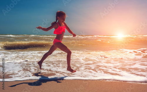 llovely girl, runs along the ocean at sunset. beautiful teen girl.