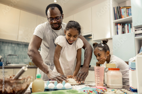 Father and daughters enjoying their traditional morning while cooking
