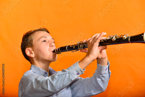 The boy performs a piece of music in the music school on the clarinet.