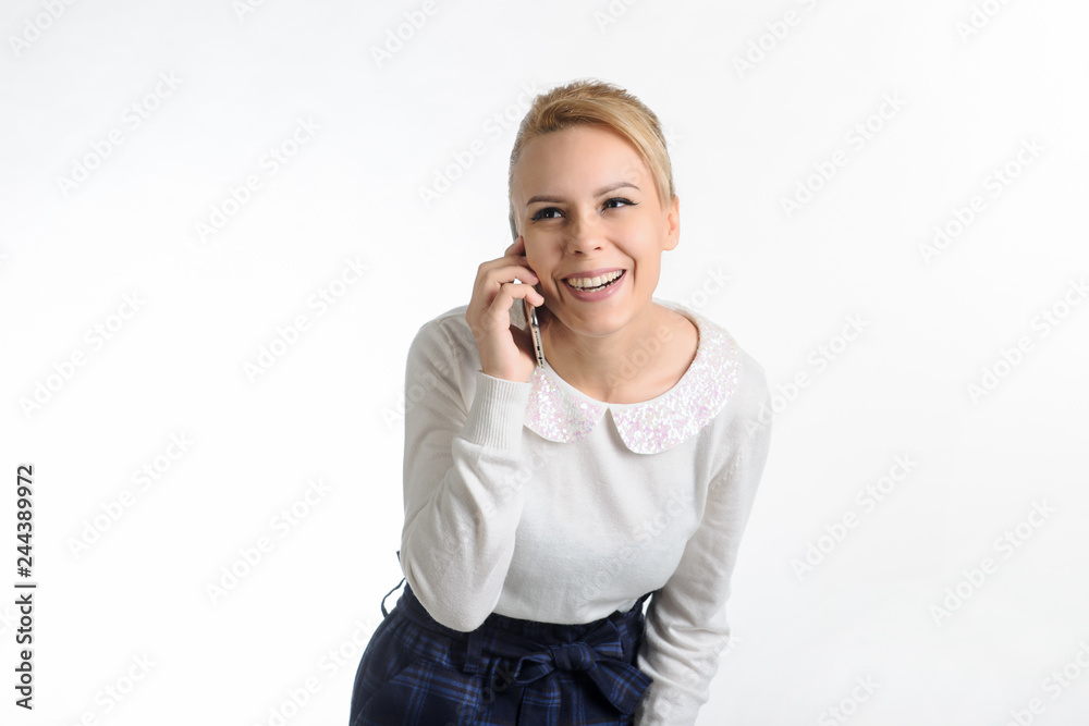 20-years blond girl in white blouse and blue skirt on white background talking on the cell phone 20-years blond girl in white blouse and blue skirt on white background talking on the cell phone