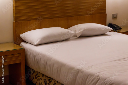 Double bed with two pillows in bedroom in soft lights