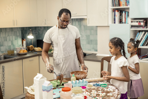 Bearded father cooking chocolate cupcakes with children