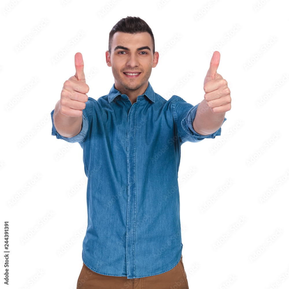 portrait of young casual man making thumbs up sign portrait of young casual man making thumbs up sign
