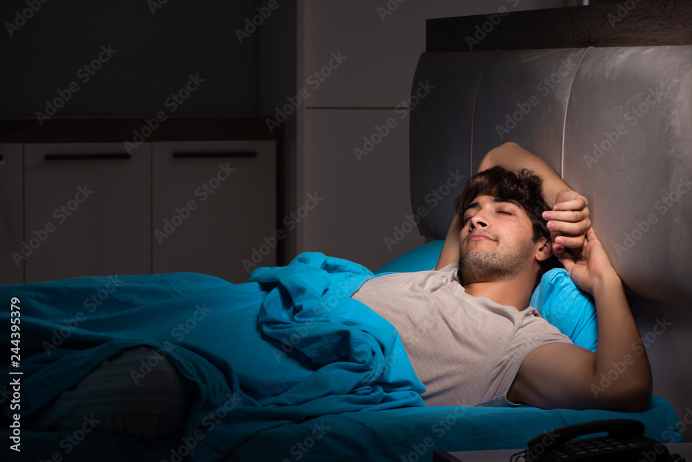 Fototapeta premium Tired exhausted man sleeping in his bed