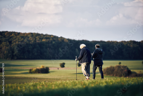 people walking along in autumn landscape with layers of agricultural fields in a moody fall scene © visualitte