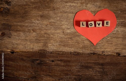 Love text written with wood blocks on red heart on rustic vintage background