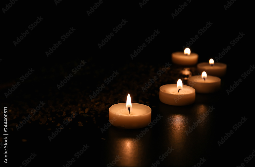 Burning candles and sea salt on table in darkness Burning candles and sea salt on table in darkness