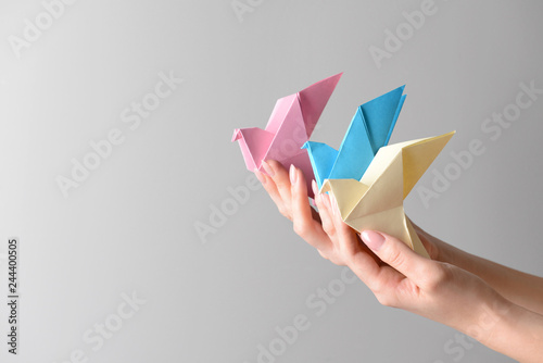 Canvas Print Female hands with origami birds on light background