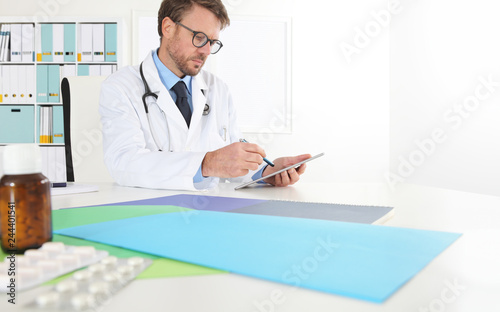 Doctor writing prescription used digital tablet at desk in medical office with drugs in the foreground, copy space web banner temolate