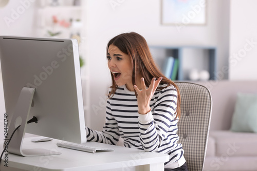Emotional young woman playing computer game at home