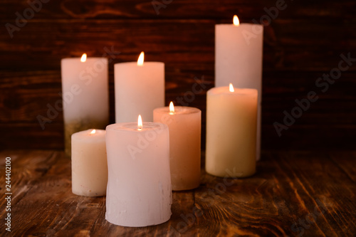 Burning wax candles on wooden table