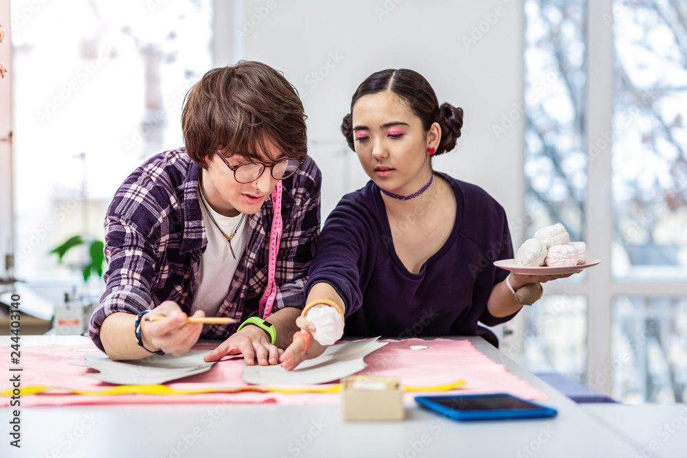 Young beautiful female asian designer advising to her colleague Young beautiful female asian designer advising to her colleague