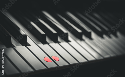 Two small red hearts on the keyboard of classic piano close up. Concept of love and romantic music