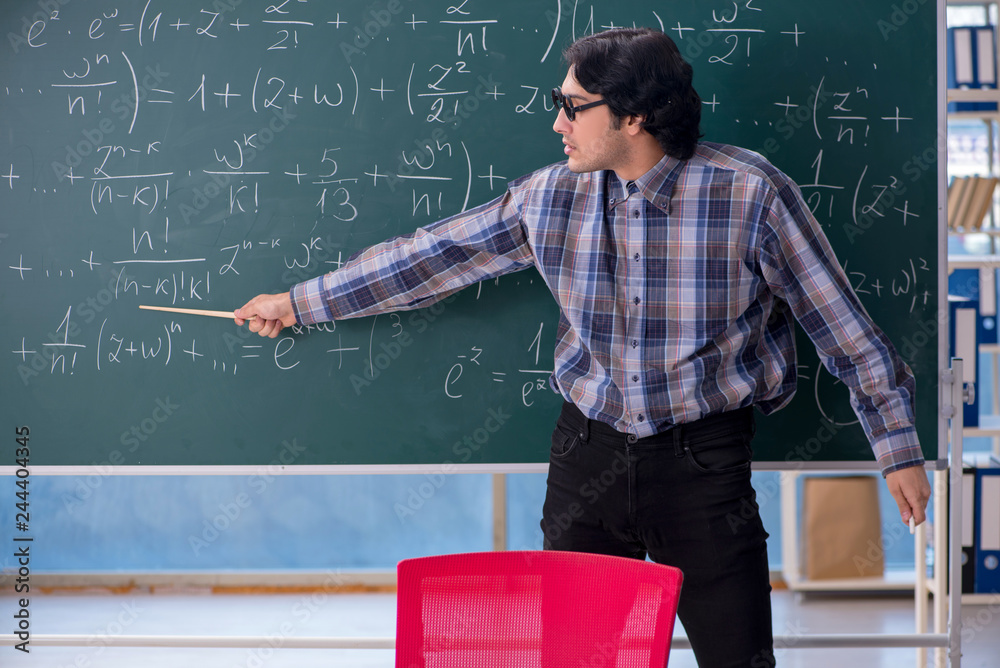 Young funny math teacher in front of chalkboard Young funny math teacher in front of chalkboard