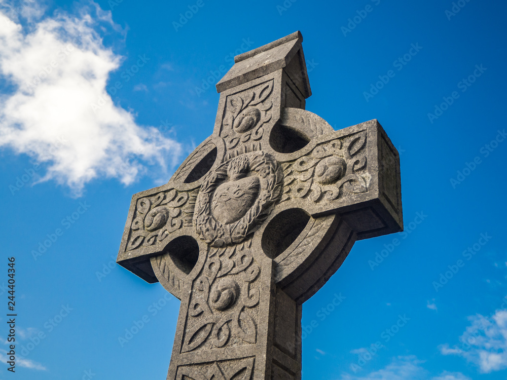 Irish celtic stone cross with hearth in the middle and blue sky backround in Ireland Irish celtic stone cross with hearth in the middle and blue sky backround in Ireland