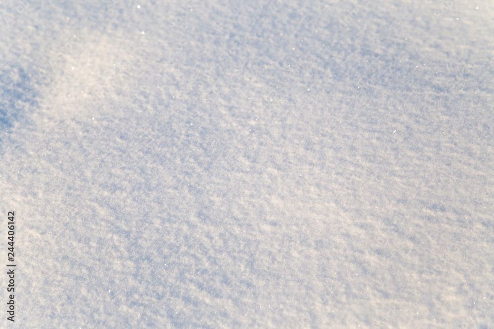 Background of white snow sparkling in the sun. Shallow depth of field