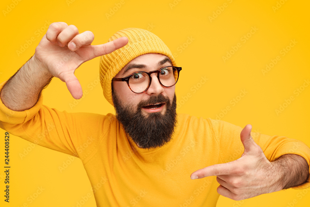 Naklejka premium Bearded man holding hands in shape of camera focus