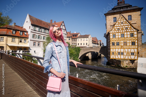 Outdoor Portrait of a beautiful young confident woman posing on the street of Bamberg. Model in stylish sun glasses. Girl looks up. Women's fashion. Sunny day.